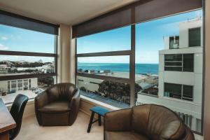 a living room with two chairs and a view of the ocean at Liardett Penthouse - Inner city accommodation in New Plymouth