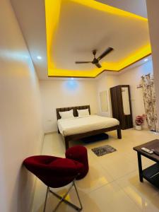 卡兰古特peppy Beach Inn Goa的一间卧室，有一张床和一把红椅子