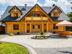 una casa de madera con un banco delante en Agroturystyka Olszynka en Skopanie