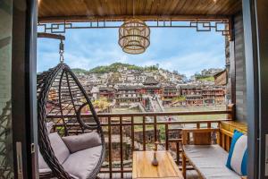 a swing on a balcony with a view of a city at Fenghuang Sulv Yunzhu River View Homestay in Fenghuang