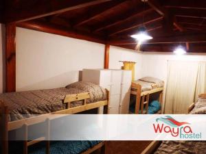 a room with two beds and a refrigerator at Wayra Hostel in La Rioja