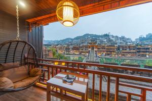a balcony with a hammock and a view of a city at Fenghuang Sulv Yunzhu River View Homestay in Fenghuang +36 photos