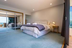 une chambre avec deux lits et un grand miroir dans l'établissement Waterfront On Woolcombe - 4BR holiday apartment, à New Plymouth