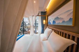 a bed with white pillows in a room with a window at Fenghuang Sulv Yunzhu River View Homestay in Fenghuang