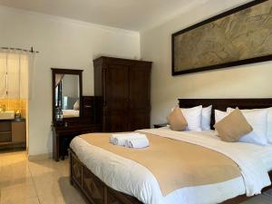 ein Schlafzimmer mit einem großen Bett und einem Spiegel in der Unterkunft Tendan Residence Hotel in Legian