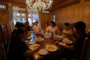 a group of people sitting around a table eating food at halloween palace in Srinagar