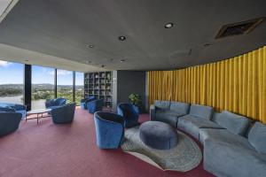 a living room with couches and a table and chairs at Sleek 2-Bed Apartment with Rooftop Garden Access in Belconnen