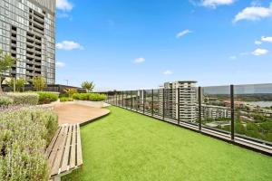 a walkway with a bench and grass on a balcony at Sleek 2-Bed Apartment with Rooftop Garden Access in Belconnen