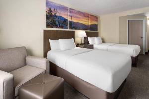 two beds in a hotel room with a chair and a couch at Days Inn by Wyndham Penn State in State College +41 photos