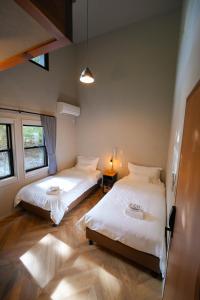 two beds in a room with two windows at Fuji Elegance Hotel in Yamanakako