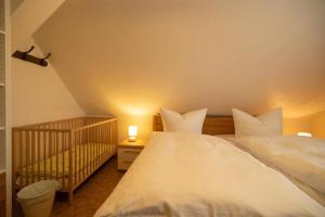 een slaapkamer met 2 witte bedden en een wieg bij Ferienhof Laibold-Evers in Hofbieber