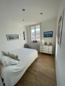 a white bedroom with a bed and a window at L'Escale Sètoise in Sète