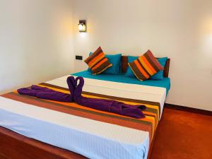a bedroom with a large bed with colorful pillows at Liyara Lodge Sigiriya in Sigiriya