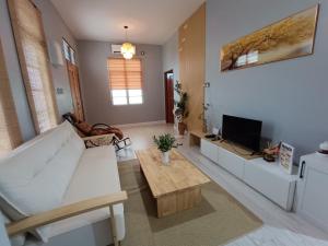 a living room with a white couch and a tv at Idaman Homestay Ayer Tawar Tok Bali in Pasir Puteh