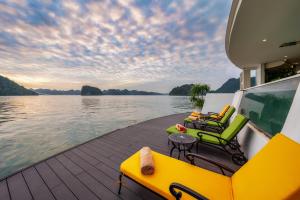 a boat deck with chairs and tables on a body of water at L'amour Cruise in Ha Long