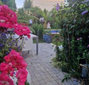 Un jardín con flores rosas, una mesa y un patio. en Chambre hôtes nichée sous les toits, en Rennes