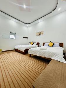 two beds in a room with white walls and wooden floors at Golden Hotel in Buon Ma Thuot