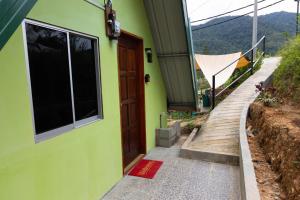 a green house with a wooden door and a pathway at Kanso Hill Lowii Cottage in Kampong Kundassan