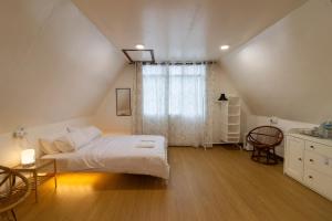 a bedroom with a white bed and a window at Kanso Hill Lowii Cottage in Kampong Kundassan