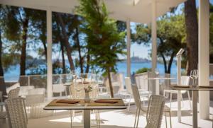 a patio with tables and chairs with a view of the water at Maistra Select Family Hotel Amarin in Rovinj