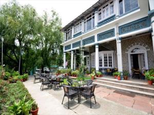 eine Terrasse mit Tischen und Stühlen vor einem Gebäude in der Unterkunft Belvedere Palace Nainital in Nainital