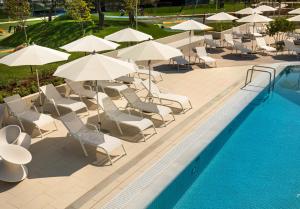 a pool with white chairs and umbrellas next to a swimming pool at Maistra Select Family Hotel Amarin in Rovinj