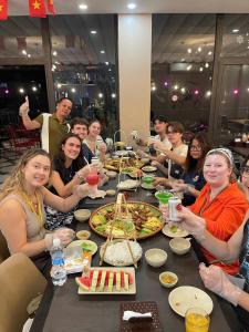 un grupo de personas sentadas alrededor de una mesa comiendo pizza en Catba Paddy House, en Cat Ba
