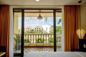a bedroom with a view of a balcony at Virgo Villa Quê Hội An in Hoi An