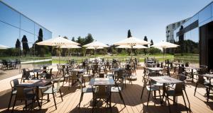 an empty patio with tables and chairs and umbrellas at Maistra Select Family Hotel Amarin in Rovinj