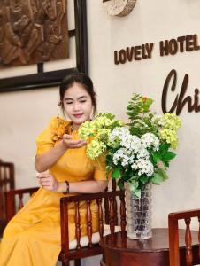 a woman in a yellow dress sitting next to a vase of flowers at Virgo Villa Quê Hội An in Hoi An