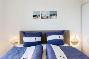 2 letti in una camera con cuscini bianchi e blu di Haus Kniepsand, Wohnung Treibsand a Wittdün
