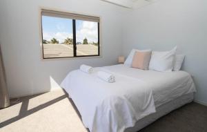a white bedroom with a large bed and a window at Aqua Vista On Arden - beachfront bach in Oakura in Oakura