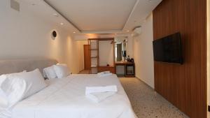 a bedroom with a white bed with a flat screen tv at BK Hotel in Fethiye