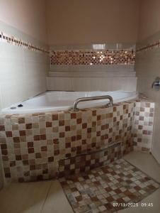 a bath tub in a bathroom with a tiled floor at Nomanini Guesthouse in Nelspruit