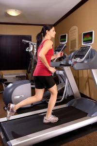 a woman running on a treadmill in a gym at Folk Inn Ontario Airport in Ontario