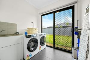 a laundry room with a washing machine and a window at Seednest BBQ Cozy Family house in Alfredton