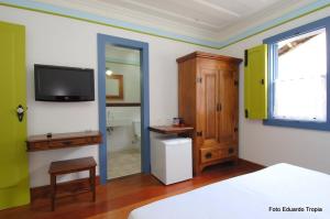 Pousada Laços de Minas في أورو بريتو: غرفة نوم مع سرير وتلفزيون على الحائط