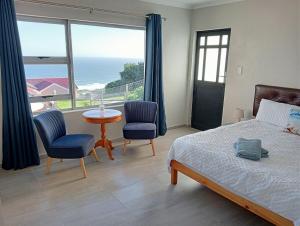 a bedroom with a bed and a table and chairs at See n Bos in Gqeberha