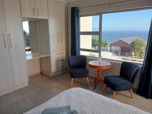a bedroom with a window and two chairs and a table at See n Bos in Gqeberha
