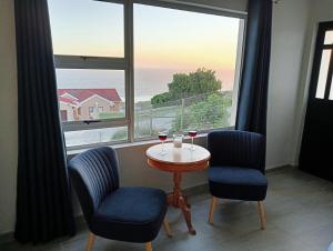 a table with two chairs and wine glasses in front of a window at See n Bos in Gqeberha +30 photos