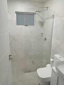 a white bathroom with a shower and a toilet at See n Bos in Gqeberha