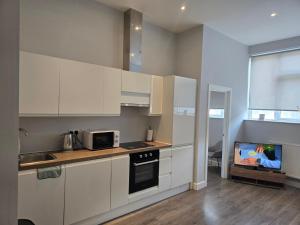 a kitchen with white cabinets and a tv in it at Chris cosy retreat in Buckinghamshire