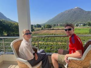 een man en een vrouw zitten op stoelen op een veranda bij Hotel Divine Palace Pushkar in Pushkar