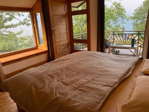 Bett in einem Zimmer mit 2 Fenstern in der Unterkunft The Goat Village in Bhatwāri