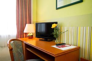 a desk with a television and a vase with a flower on it at Hotel Neun 3/4 in Celle