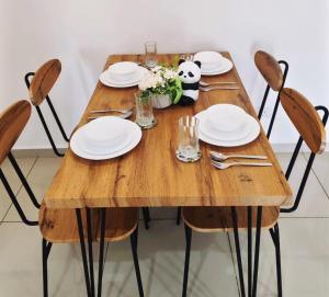 ein Holztisch mit Tellern und Gläsern und einem Panda darauf in der Unterkunft 2-5pax Panda Homestay Midas Seri Alam TVGame Senibong in Masai