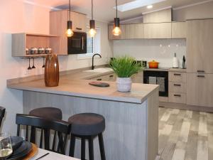 a kitchen with a island with stools in it at 38 At The Sanctuary Lodges - Uk50850 in Carnguwch +30 photos