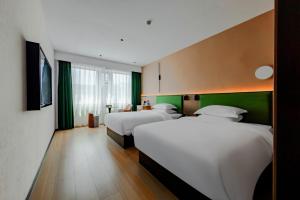 two beds in a hotel room with green walls at Fengqi Wutong Holiday Hotel - Changsha Wuyi Avenue Railway Station Metro Station Branch in Changsha +54 photos