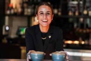 a woman sitting at a table with two cups of coffee at Boutique Hotel Herman K in Copenhagen