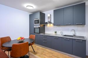 a kitchen with blue cabinets and a table with a bowl of fruit at Apartment Fortuna in Trpanj